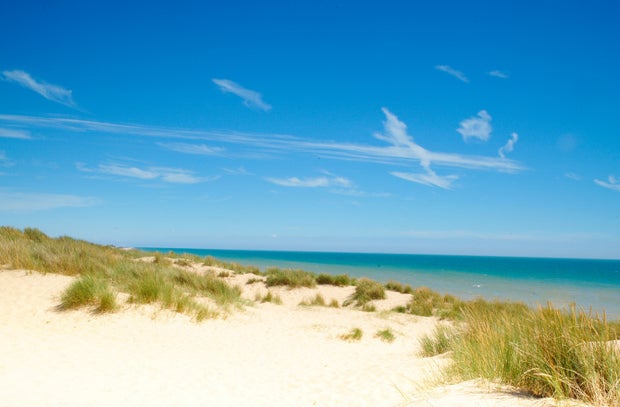 The pure sand of Camber beach under clear blue sunny skies.