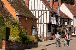 Friends walking their bikes down a picturesque street in pretty Kersey village