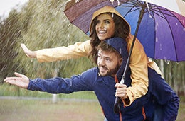 A couple enjoying the rain with their umbrellas