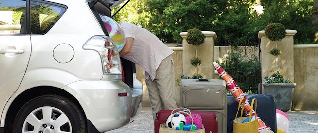 Car boot being packed with colourful luggage