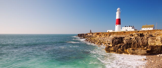 A lighthouse on a white cliff overlooks the sea