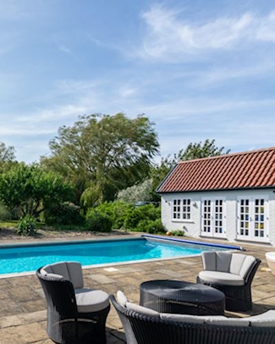 A seating area sits beside an outdoor swimming pool