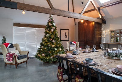 A dining room with a large table dressed for Christmas and a big decorated tree at the far end.