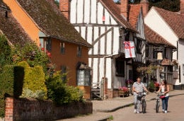 Suffolk’s Magical Wool Towns Friends walking their bikes down a picturesque street in pretty Kersey village