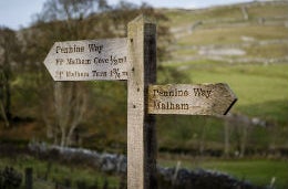 A sign on the Penine Way with green countryside in the background.